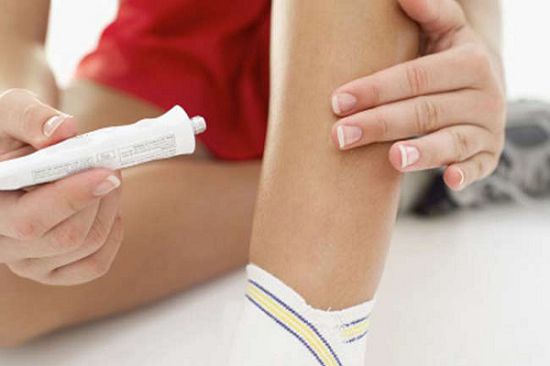 Close-up of a woman applying ointment to her leg